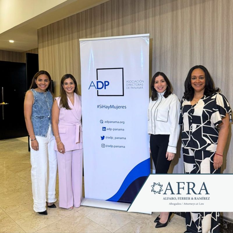 Socias y asociada de la firma AFRA posando sonrientes junto al banner de la Asociación Directoras de Panamá (ADP) durante el evento anual.